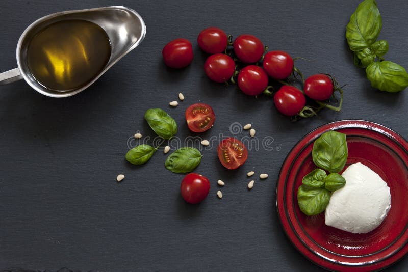 Zakończenie czerwoni czereśniowi pomidory z białym mozzarella serem, oliwa z oliwek i zielonymi liśćmi basil na czarnym tle, zdjęcie royalty free Zakończenie czerwoni czereśniowi pomidory z białym mozzarella serem, oliwa z oliwek i zielonymi liśćmi basil na czarnym tle, zdjęcie royalty free