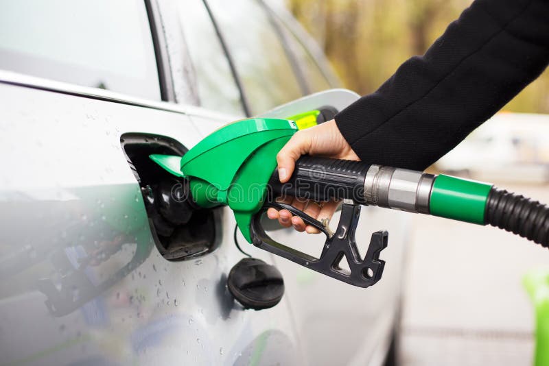 Zakończenie fotografia trzyma paliwową pompę i refilling samochód przy stacją benzynową ręka