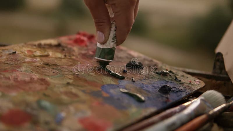 Zakończenie kobiety ` s ręki artysta up gniesie out farby od tubki na palecie Przygotowywać dla sztuki pracy outdoors
