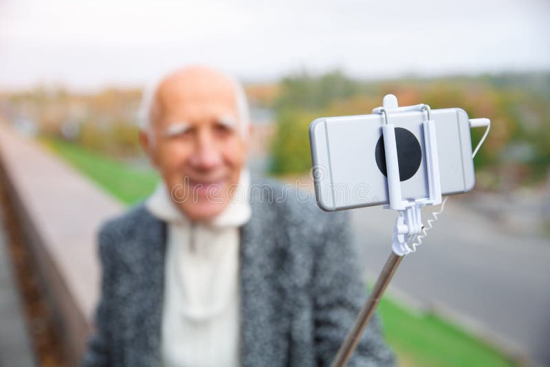 Zakończenie monopod z telefonem w rękach starszy mężczyzna fotografia royalty free Zakończenie monopod z telefonem w rękach starszy mężczyzna fotografia royalty free