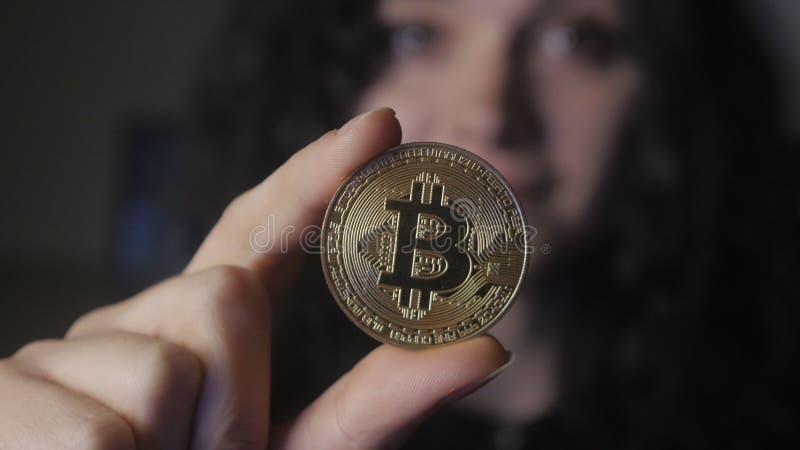 Zakończenie młoda kobieta up trzyma złocistego Bitcoin w ręce minować i handlować