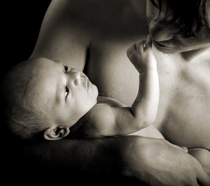 Close up of a newborn touching his fathers face in monochrome with sepia toning. Close up of a newborn touching his fathers face in monochrome with sepia toning