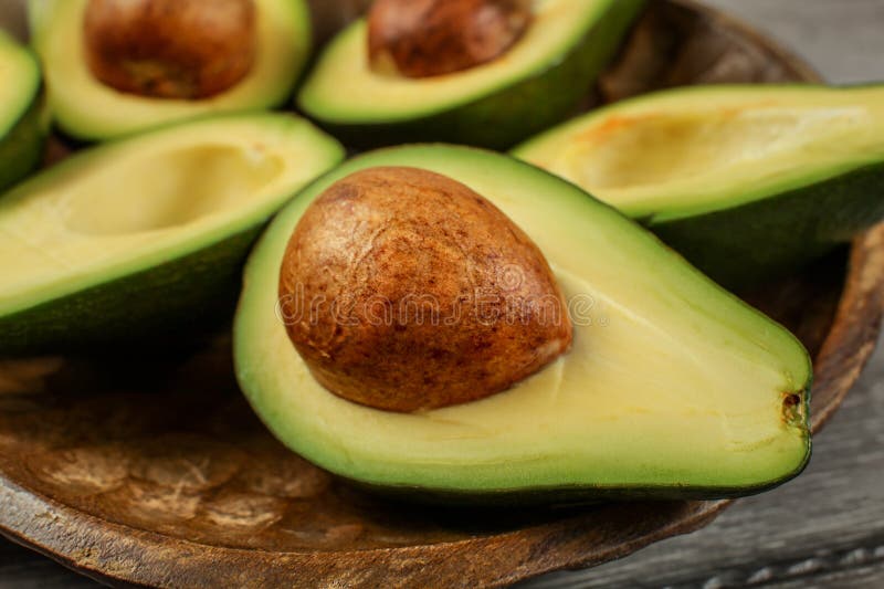 Zakończenie w górę fotografii avocado połówki na drewnianym rzeźbiącym pucharze, szczegół o zdjęcia royalty free