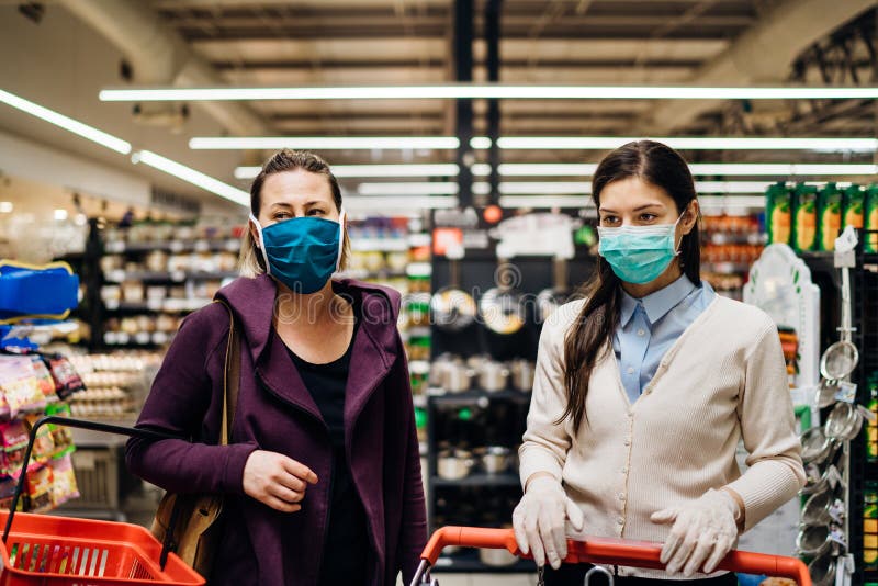 Shoppers with masks buying for groceries due to coronavirus pandemic in grocery store.COVID-19 food shopping.Quarantine preparation.Panic buying and stockpiling.Social distancing in supermarket. Shoppers with masks buying for groceries due to coronavirus pandemic in grocery store.COVID-19 food shopping.Quarantine preparation.Panic buying and stockpiling.Social distancing in supermarket