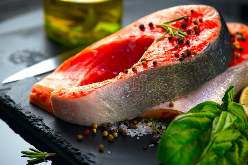 Zalm Het ruwe lapje vlees van forelvissen met kruiden en citroen op zwarte leiachtergrond Het koken, zeevruchten Het gezonde Eten stock foto Zalm Het ruwe lapje vlees van forelvissen met kruiden en citroen op zwarte leiachtergrond Het koken, zeevruchten Het gezonde Eten stock foto