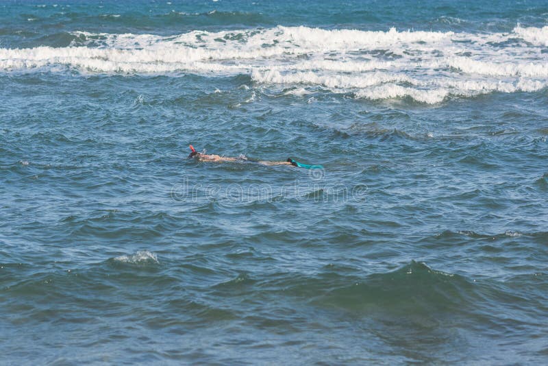 Zambullidas del hombre en la máscara y el tubo que bucean de las aletas que nadan en las ondas de la tormenta foto de archivo Zambullidas del hombre en la máscara y el tubo que bucean de las aletas que nadan en las ondas de la tormenta foto de archivo