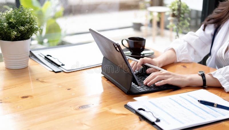 Close up Business woman using calculator and laptop for do math finance on wooden desk in office and business working background, tax, accounting, statistics and analytic research concept. Close up Business woman using calculator and laptop for do math finance on wooden desk in office and business working background, tax, accounting, statistics and analytic research concept