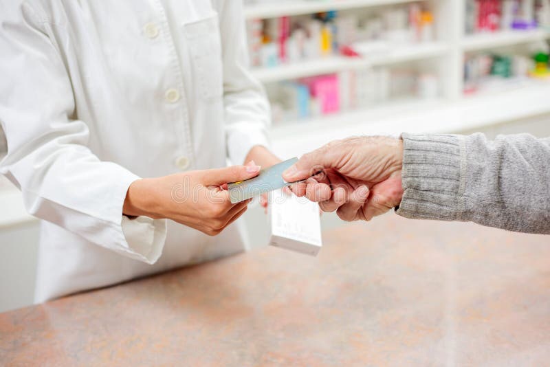 Zamknięcie starszego pacjenta płci męskiej wystawiającego kartę kredytową młodej kobiecie farmaceuty fotografia royalty free
