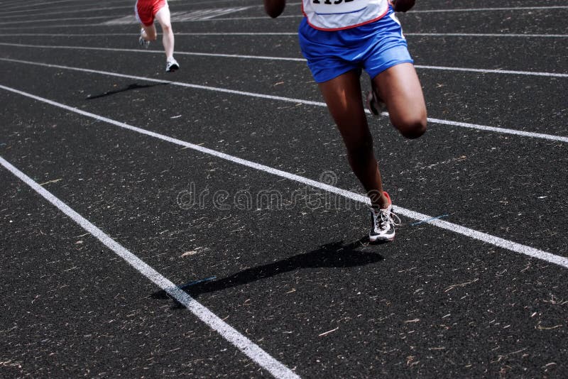 A pair of runners run down the track. A pair of runners run down the track