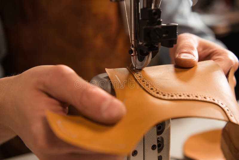 Close up of a cobbler stitching a part of the shoe at a workshop. Close up of a cobbler stitching a part of the shoe at a workshop