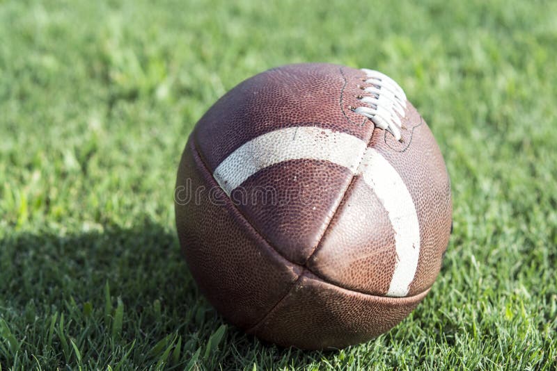 Zamyka up futbolu amerykańskiego obsiadanie na trawie zdjęcie stock Zamyka up futbolu amerykańskiego obsiadanie na trawie zdjęcie stock