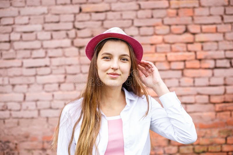 Zamyka w g?r? portreta pi?kna elegancka dzieciak dziewczyna w kapeluszowej pobliskiej r??owej ?cianie z cegie? jako t?o obraz royalty free Zamyka w g?r? portreta pi?kna elegancka dzieciak dziewczyna w kapeluszowej pobliskiej r??owej ?cianie z cegie? jako t?o obraz royalty free