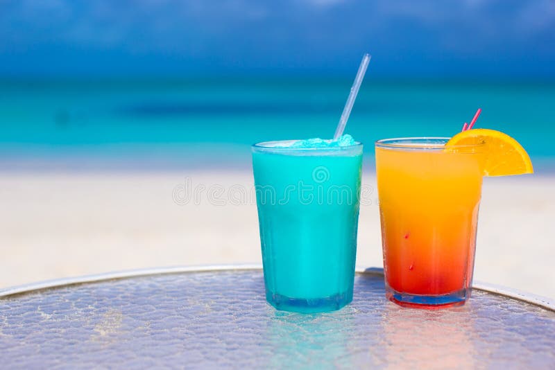 Zamyka w górę Błękitnego Curacao i mango koktajlu na białej piaskowatej plaży zdjęcia stock Zamyka w górę Błękitnego Curacao i mango koktajlu na białej piaskowatej plaży zdjęcia stock