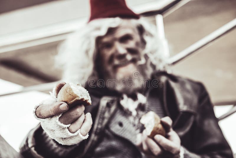 Take one. Blurred close up of old smiling almsman whos holding pieces of baking and sincerely sharing it with photographer. Take one. Blurred close up of old smiling almsman whos holding pieces of baking and sincerely sharing it with photographer.