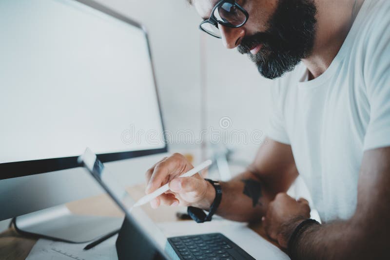 Zamyka w górę widoku brodaty mężczyzna w białym tshirt pracuje z przenośnym pastylka komputerem Projektant rysuje cyfrowych plany obrazy stock Zamyka w górę widoku brodaty mężczyzna w białym tshirt pracuje z przenośnym pastylka komputerem Projektant rysuje cyfrowych plany obrazy stock