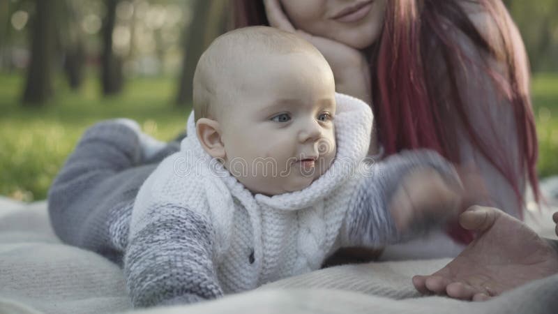 Zamykanie uroczego, uroczego kaukaskiego chłopca leżącego na kocu bawiącego się uśmiechniętymi młodymi ojcami i matką. portret