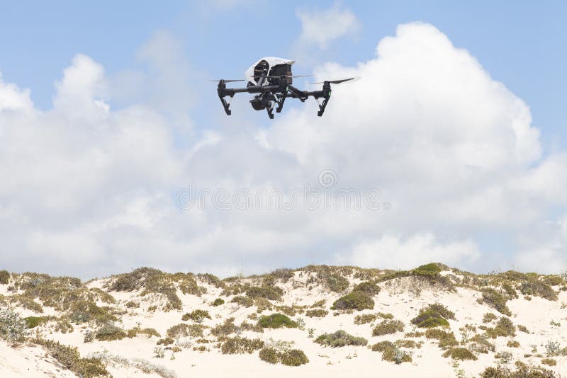 Zangão branco do quadcopter com a câmera da foto sobre as dunas foto de stock Zangão branco do quadcopter com a câmera da foto sobre as dunas foto de stock