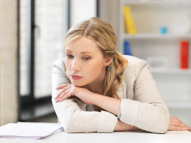 Indoor picture of bored and tired woman behind the table. Indoor picture of bored and tired woman behind the table