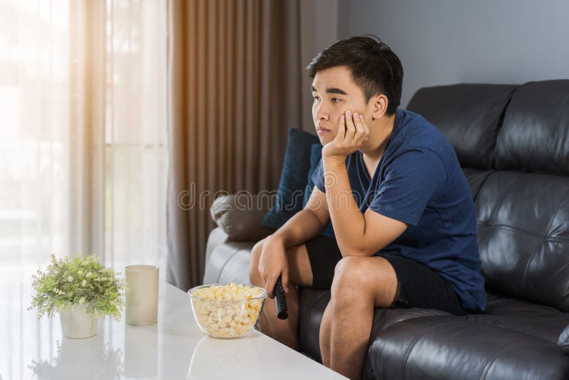 Zanudzający mężczyzna ogląda tv i obsiadanie na kanapie w żywym pokoju obrazy royalty free Zanudzający mężczyzna ogląda tv i obsiadanie na kanapie w żywym pokoju obrazy royalty free