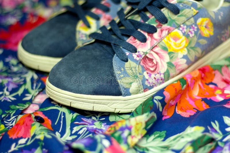 Zapatillas de deporte con la impresión floral en el fondo de la camisa del ` s de las mujeres con colores brillantes imagen de archivo libre de regalías Zapatillas de deporte con la impresión floral en el fondo de la camisa del ` s de las mujeres con colores brillantes imagen de archivo libre de regalías
