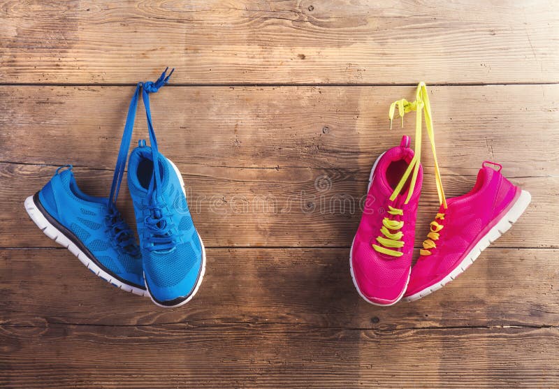 Two pairs of sneakers hang on a nail on a wooden fence background. Two pairs of sneakers hang on a nail on a wooden fence background