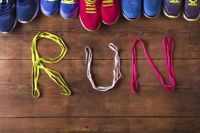 Five pairs of running shoes and shoelaces run sign on a wooden floor background. Five pairs of running shoes and shoelaces run sign on a wooden floor background