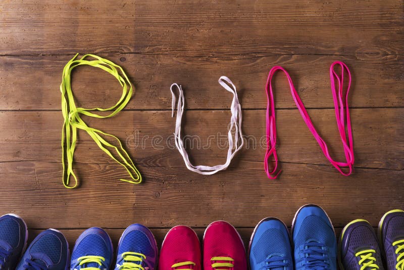 Five pairs of running shoes and shoelaces run sign on a wooden floor background. Five pairs of running shoes and shoelaces run sign on a wooden floor background