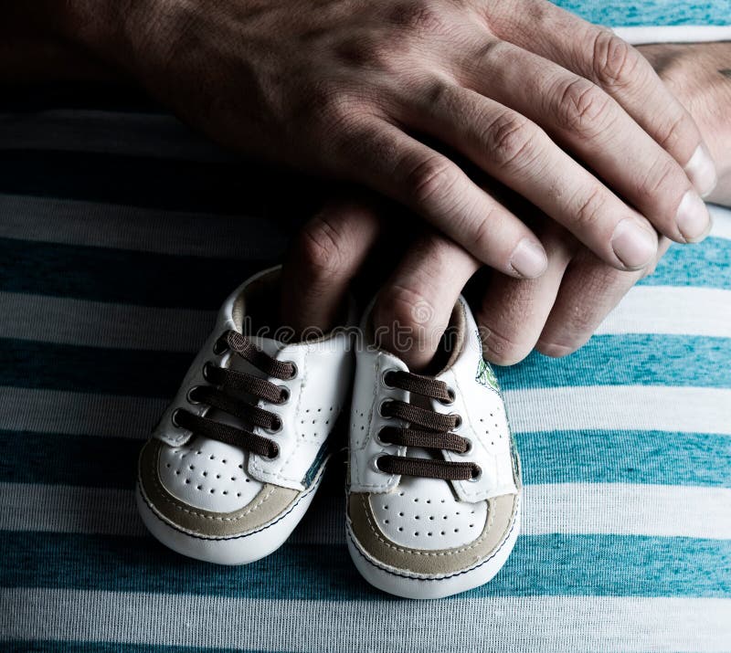 Zapatos de bebé de la explotación agrícola de la mujer embarazada en su vientre imagen de archivo libre de regalías Zapatos de bebé de la explotación agrícola de la mujer embarazada en su vientre imagen de archivo libre de regalías