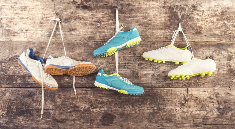 Three pairs of sports shoes hang on a nail on a wooden fence background. Three pairs of sports shoes hang on a nail on a wooden fence background