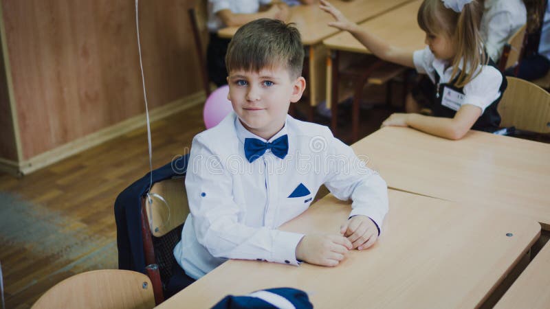 Zaporozhye Ukraina, Wrzesień, - 1, 2018: portret pierwszy równiarka w białej koszula i błękitny łęku krawata obsiadanie przy biur obrazy royalty free Zaporozhye Ukraina, Wrzesień, - 1, 2018: portret pierwszy równiarka w białej koszula i błękitny łęku krawata obsiadanie przy biur obrazy royalty free