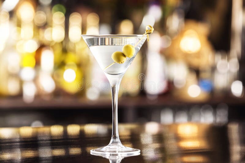 Zbliżenia szkło Martini suchy koktajl z oliwkami przy baru kontuarem obrazy stock Zbliżenia szkło Martini suchy koktajl z oliwkami przy baru kontuarem obrazy stock