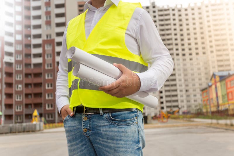 Zbliżenie architekt w zbawczej kamizelce pozuje z projektami przy ne obraz stock