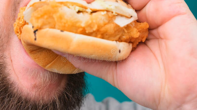 Zbliżenie człowieka gryzącego hamburgera na kluczu chromy. koncepcja niezdrowego i niezdrowego żywienia wysoki poziom cholesterolu