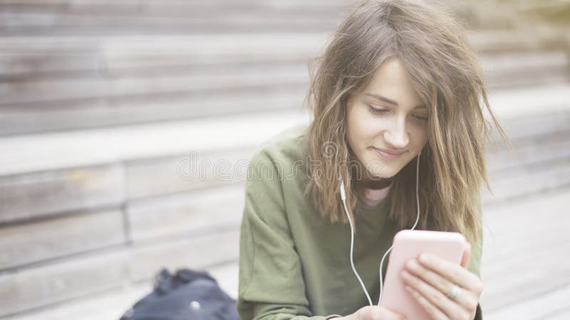 Zbliżenie młoda uśmiechnięta ładna dziewczyna trzyma telefon słucha muzyka fotografia royalty free Zbliżenie młoda uśmiechnięta ładna dziewczyna trzyma telefon słucha muzyka fotografia royalty free