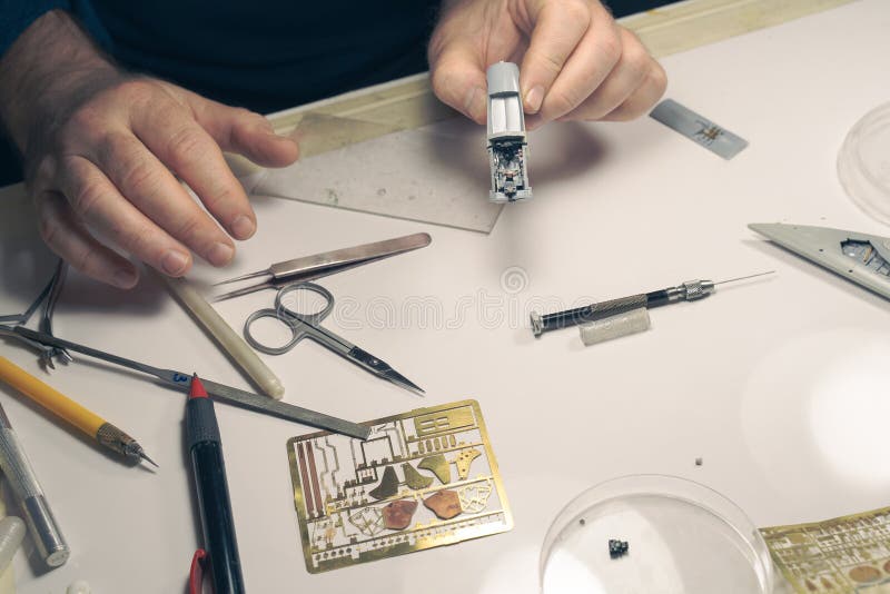 Zbliżenie rąk ludzkich trzymających plastikową część samolotu, z wieloma drobnymi szczegółami zestawionymi i pomalowanymi ręcznie. zdjęcie stock