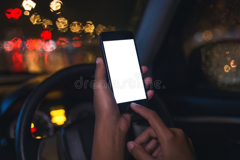 Zbliżenie ręka używać telefon wśrodku samochodu na nocy w mieście obraz stock Zbliżenie ręka używać telefon wśrodku samochodu na nocy w mieście obraz stock
