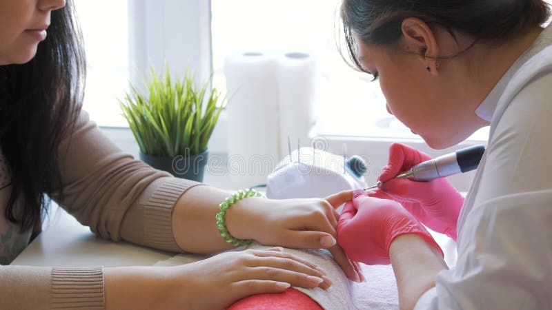 Zbliżenie strzał mistrz używa elektryczną maszynę usuwać gwoździa połysk podczas manicure'u w salonie narzędzia zbiory wideo Zbliżenie strzał mistrz używa elektryczną maszynę usuwać gwoździa połysk podczas manicure'u w salonie narzędzia zbiory wideo