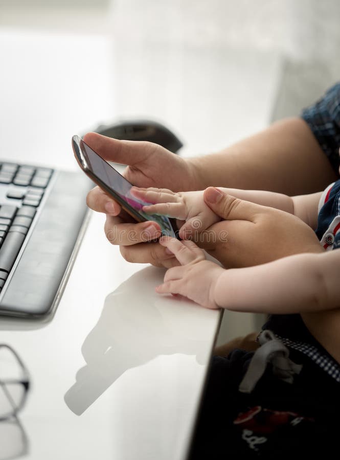 Zbliżenie wizerunek samiec wręcza mienia dziecka i smartphone wzruszający ekran sensorowy obrazy stock Zbliżenie wizerunek samiec wręcza mienia dziecka i smartphone wzruszający ekran sensorowy obrazy stock