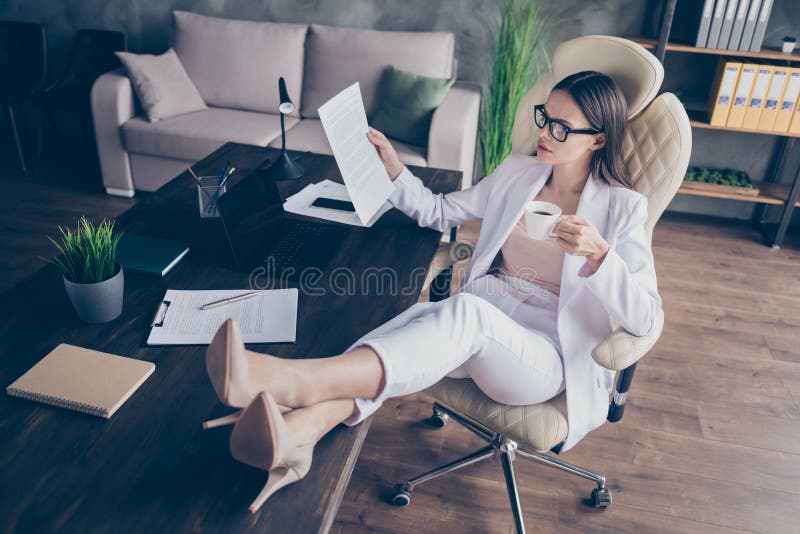 Zdjęcie atrakcyjnych dla firm nogów szpilki na biurku praca zdalna praca spoczynek picie gorąca kawa przeczytaj