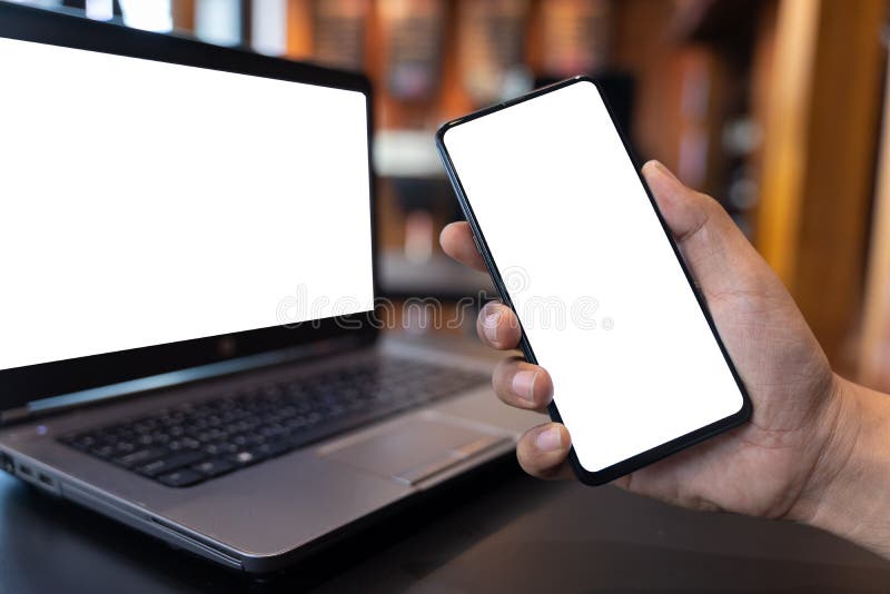 Zdjęcie makijażu ręcznego trzymającego czarny telefon komórkowy z białym pustym ekranem i czarnym laptopem w kawiarni, biały pust obrazy stock Zdjęcie makijażu ręcznego trzymającego czarny telefon komórkowy z białym pustym ekranem i czarnym laptopem w kawiarni, biały pust obrazy stock