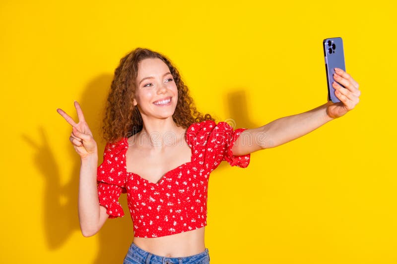 Zdjęcie portret atrakcyjnej młodej kobiety selfie photo vsign ubrana stylowe czerwone ubrania wyizolowane w żółtym kolorze obrazy royalty free