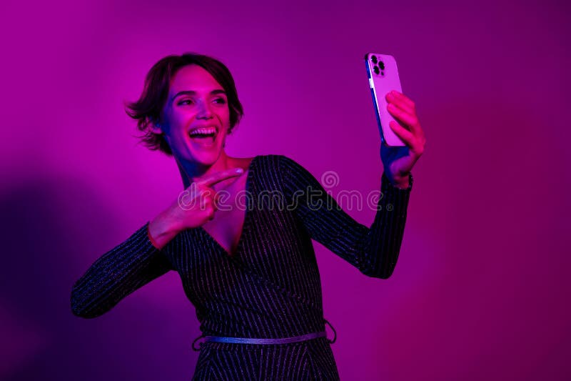 Zdjęcie portret pięknej młodej dziewczyny selfie punkt fotograficzny gadżet ubrany stylowy strój ogólny na neon light różowy zdjęcie stock