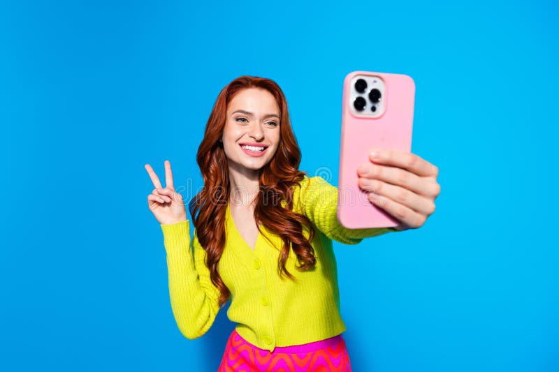 Zdjęcie portret pięknej młodej dziewczyny zrobić selfie zdjęcia vsign nosić modny żółty strój odizolowany na niebieskim tle fotografia royalty free