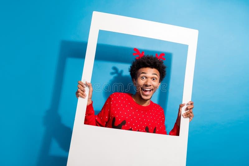 Zdjęcie portret przystojnego młodego faceta trzymającego ramkę fotograficzną ubranego czerwony sweter świąteczny świętować zimowe zdjęcie stock
