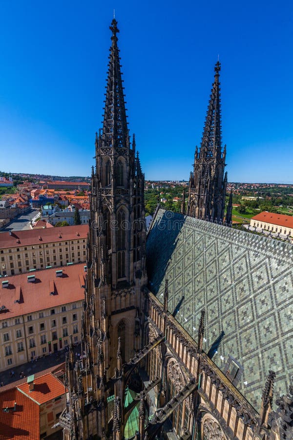 Zdjęcie z lotu ptaka przedstawiające iglice gotyckiej katedry wznoszące się ponad panoramą miasta z budynkami o czerwonych dachach pod błękitnym niebem