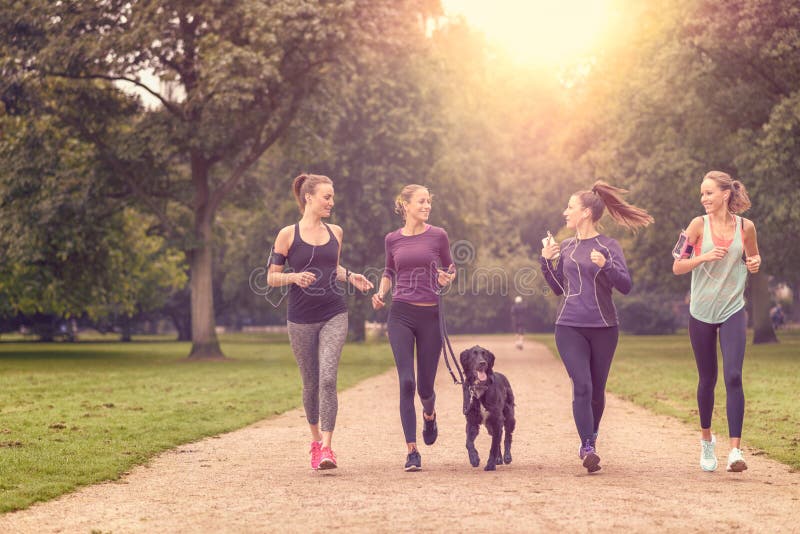 Zdrowe kobiety Jogging przy parkiem z psem zdjęcie stock Zdrowe kobiety Jogging przy parkiem z psem zdjęcie stock
