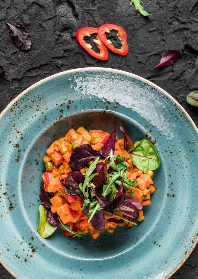 Zdrowego weganinu curry'ego dyniowa sałatka z z pieprzami i pomidorem w ceramicznym talerzu nad ciemnym tłem Zdrowy jedzenie, czy fotografia royalty free Zdrowego weganinu curry'ego dyniowa sałatka z z pieprzami i pomidorem w ceramicznym talerzu nad ciemnym tłem Zdrowy jedzenie, czy fotografia royalty free