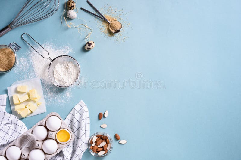 Zdrowi wypiekowi składniki - mąka, migdałowe dokrętki, masło, jajka, ciastka nad błękitnym stołowym tłem Piekarni tła rama wierzc