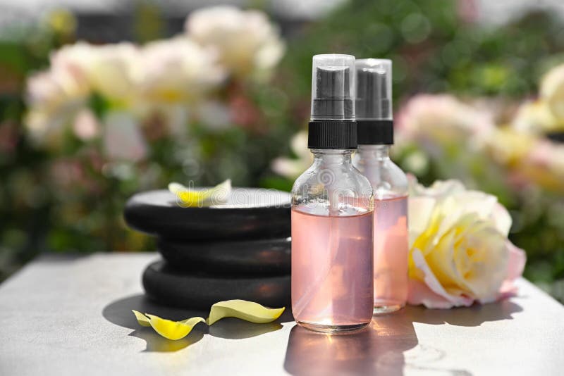 Zdrój dryluje i wzrastał na stole w ogródzie, butelki toner z istotnym olejem Harmonia i zen zdjęcie stock Zdrój dryluje i wzrastał na stole w ogródzie, butelki toner z istotnym olejem Harmonia i zen zdjęcie stock