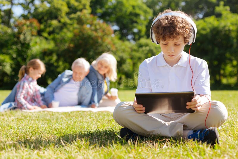 Zeer aandachtige jongen die naar beneden op de tablet kijken royalty-vrije stock afbeeldingen Zeer aandachtige jongen die naar beneden op de tablet kijken royalty-vrije stock afbeeldingen